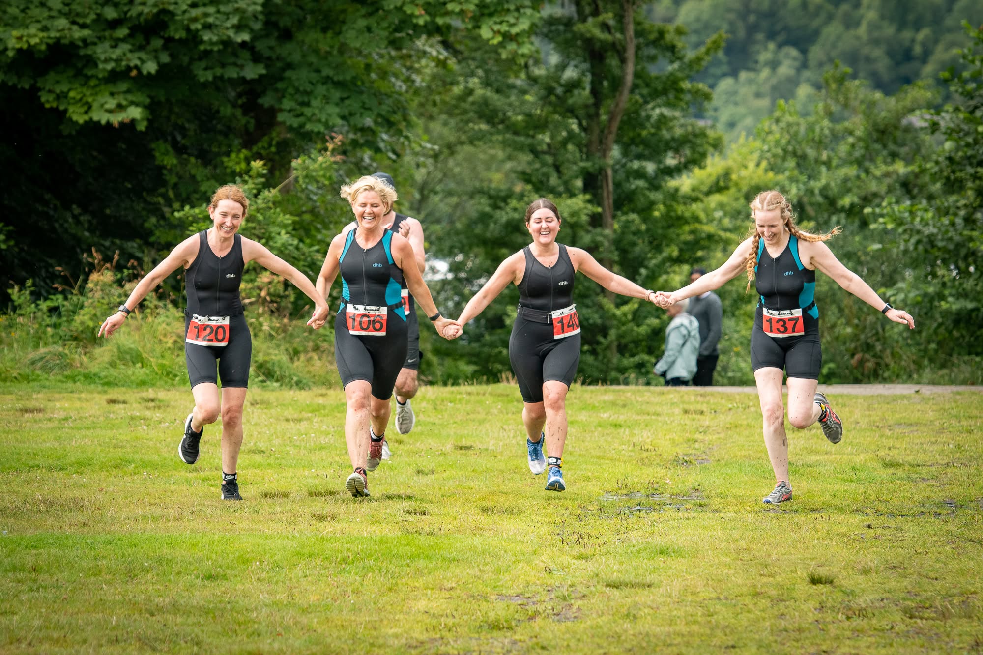 Four women holding hands and smiling as they run towards the Beastie finish