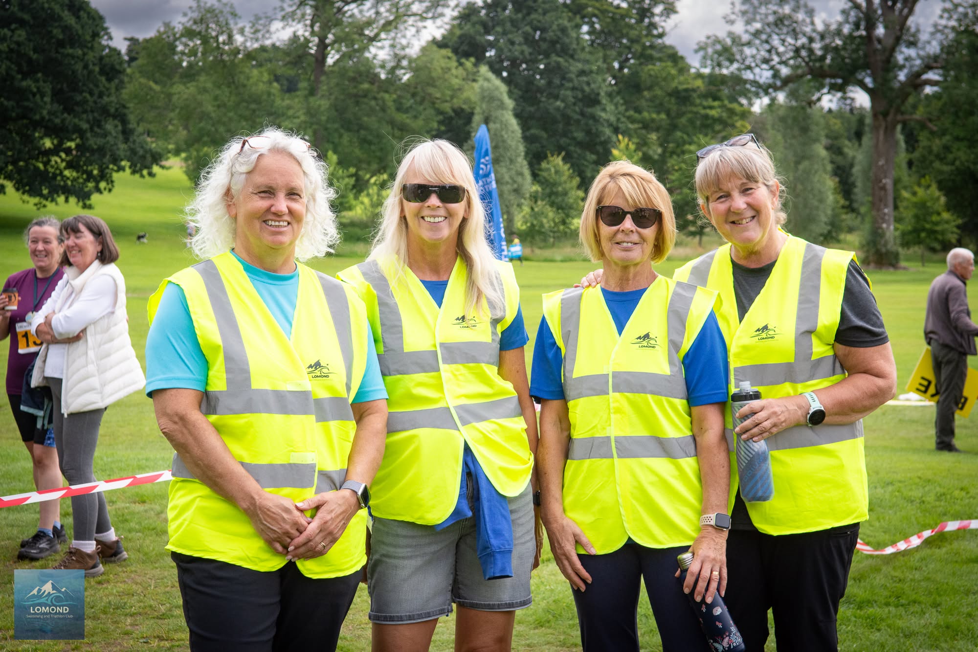 Four smiling Lomond volunteers in high-visibility vests