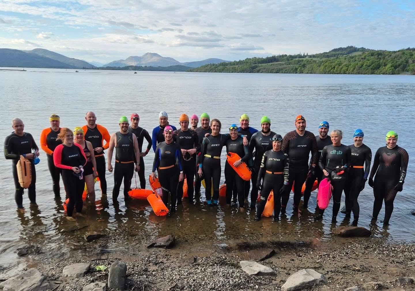 A large group of Lomond open-water swimmers standing in Loch Lomond